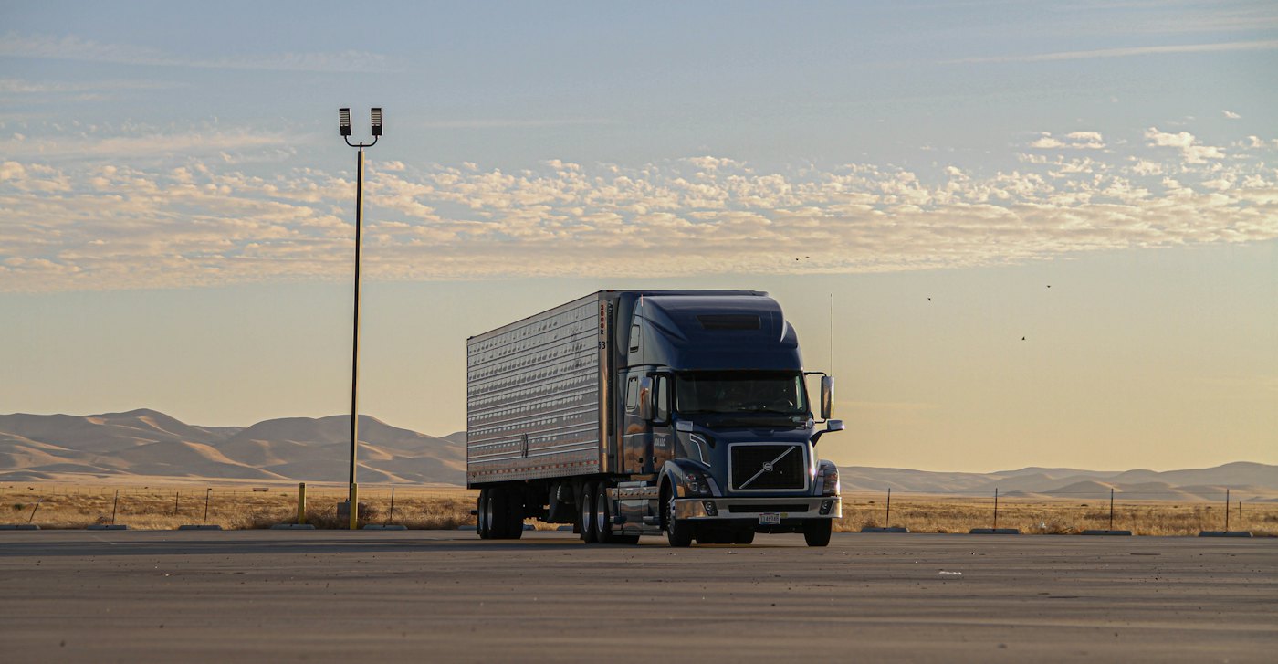 Black semi truck driving on a two-lane road