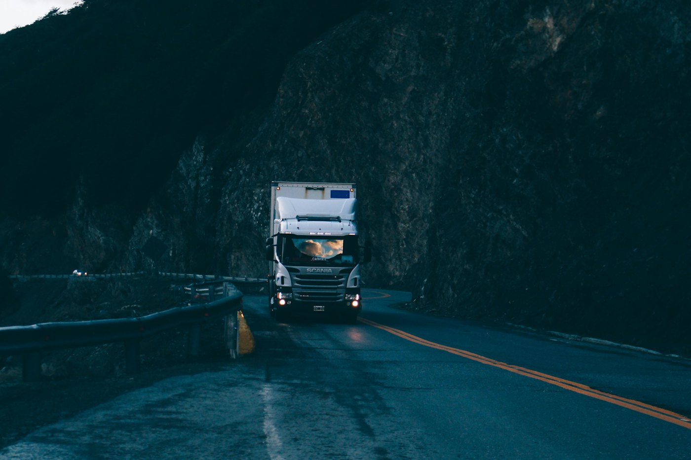 Tractor-trailer moving quickly past a highway guardrail