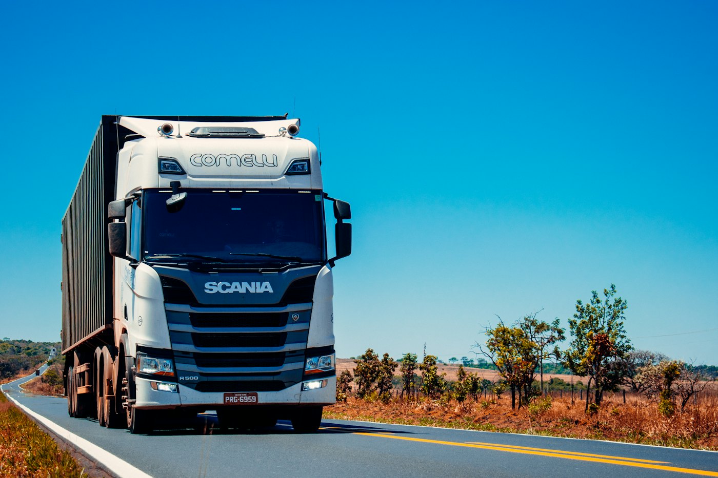 White semi truck pulling a dry van trailer on a highway